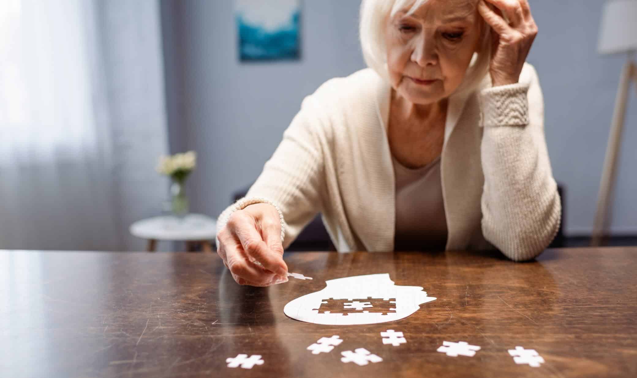Older woman completing a puzzle, illustrating cognitive changes and the importance of Alzheimer’s blood biomarkers for disease detection and assessment.