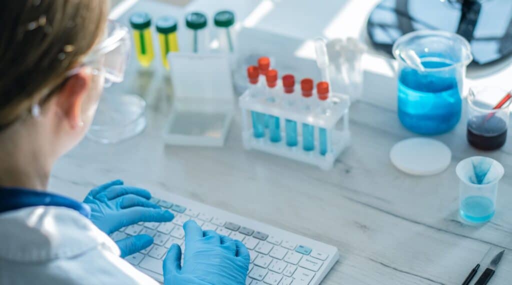 Laboratory researcher entering assay data beside sample tubes during blood biomarker analysis for LATE